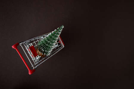 Top view of a grocery cart with snowy Christmas trees on a dark background with copy space for text. The apartment was lying. Winter, postcard template.の写真素材