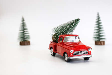 miniature red car in the back carries a Christmas tree on a white isolated background, top view. Save the space. Concept, festive Christmas mood, gift delivery. The trendの写真素材