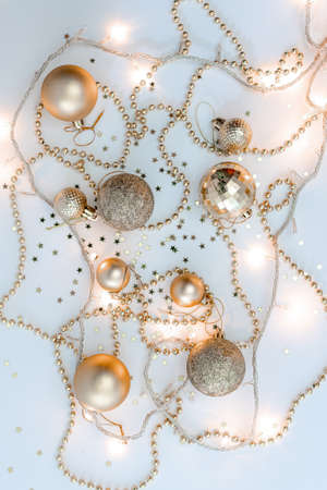 Christmas holidays composition, top view of gold Christmas decorations and garland with lights on a yellow background with copy space for text. Blur. Flat lay. Winter, postcard template.の写真素材