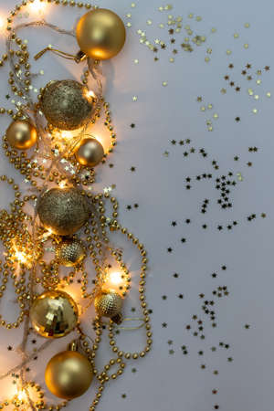 Christmas holidays composition, top view of gold Christmas decorations and garland with lights on a yellow background with copy space for text. Blur. Flat lay. Winter, postcard template.の写真素材