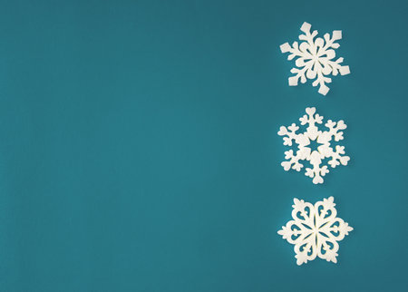 Christmas holidays composition, top view white snowflakes decoration on Cyan-acquamarine background with copy space for text. Flat lay. Winter, postcard template.の写真素材