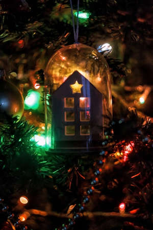 a toy in the form of a house hangs on a Christmas tree with burning lights. Silhouetteの写真素材