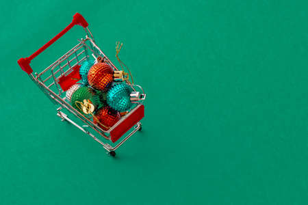 Grocery cart with Christmas balls toys on a blue-green simple background. Flat lay. Save the space. Postcard Template.の写真素材