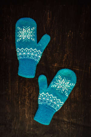 a pair of blue knitted mittens on a dark blue-green-brown wooden vintage background, copy space.の写真素材