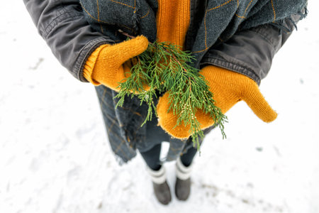 a young happy woman holds a cypress branch in yellow mittens in her hands. View from above.の写真素材