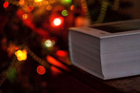 thick book on the background of a christmas tree with christmas lights.の写真素材