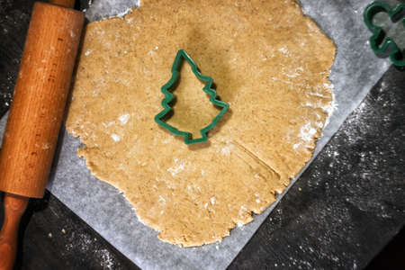 Fresh homemade dough for preparation christmas gingerbread cookies and baking cutters on scattered flour with decor. Kitchen holiday pastry background with copy space.の写真素材