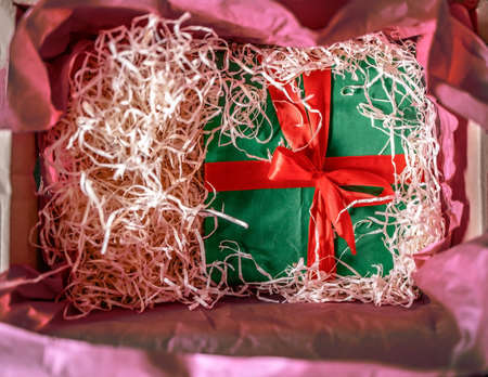 green gift box hidden in a box with shavingsの写真素材