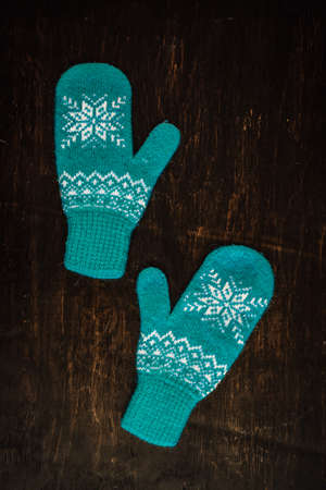 a pair of blue knitted mittens on a dark blue-green-brown wooden vintage background, copy space.の写真素材