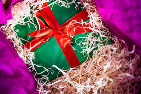 green gift box hidden in a box with shavingsの写真素材
