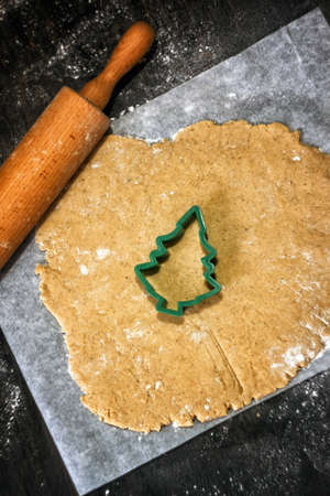 Fresh homemade dough for preparation christmas gingerbread cookies and baking cutters on scattered flour with decor. Kitchen holiday pastry background with copy space.の写真素材