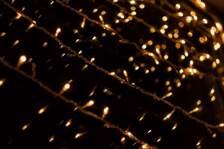 Festive window decoration at dusk. Christmas lights. the garlands glow with yellow light. Blurred photo.の写真素材