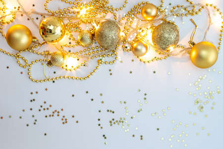 Christmas holidays composition, top view of gold Christmas decorations and garland with lights on a yellow background with copy space for text. Blur. Flat lay. Winter, postcard templateの写真素材