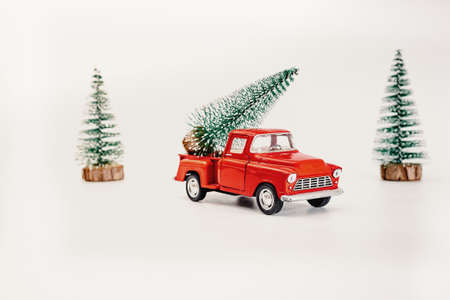 miniature red car in the back carries a Christmas tree on a white isolated background, top view. Save the space. Concept, festive Christmas mood, gift delivery. The trend.の写真素材