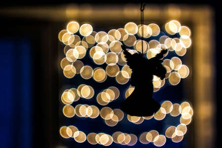 Black silhouette of an angel on a background of bokeh lights. Christmas magic conceptの写真素材