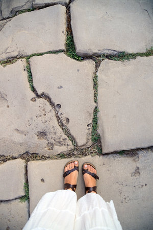 female legs in gladiator sandals on stone background, top view, copy spaceの写真素材