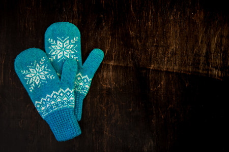 a pair of blue knitted mittens on a dark blue-green-brown woodenの写真素材
