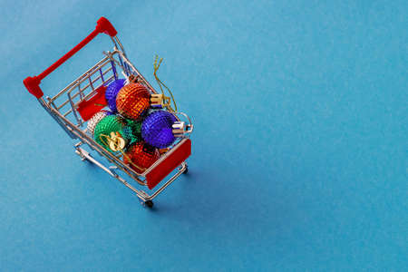 Grocery cart with Christmas balls toys on a blue-green simple background. Flat lay. Save the space. Postcard Templateの写真素材