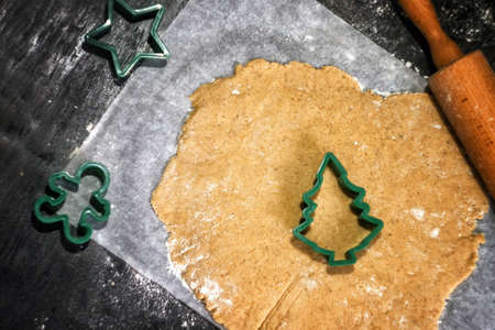 Fresh homemade dough for preparation christmas gingerbread cookies and baking cutters on scattered flour with decor. Kitchen holiday pastry background with copy spaceの写真素材