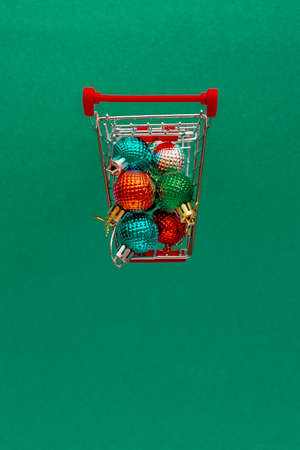 Grocery cart with Christmas balls toys on a blue-green simple background. Flat lay. Save the space. Postcard Templateの写真素材
