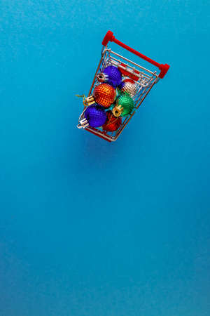 Grocery cart with Christmas balls toys on a blue-green simple background. Flat lay. Save the space. Postcard Templateの写真素材