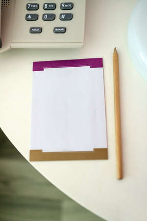 notebook and pencil on the table near the push-button phone.の写真素材