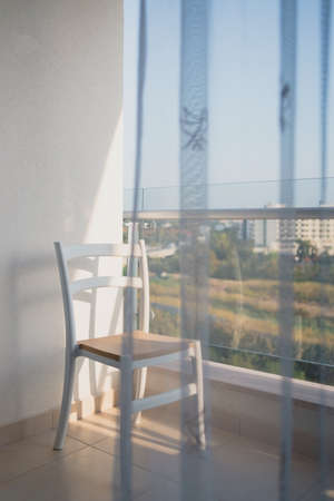 on an open minimalistic balcony overlooking the sea, there is an empty chair.の写真素材