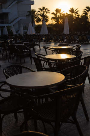 tables in a Turkish street cafe in the early morning light against the backdrop of palm treesの写真素材