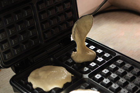 cooking Belgian waffles in a waffle iron. Pour in the dough..の写真素材