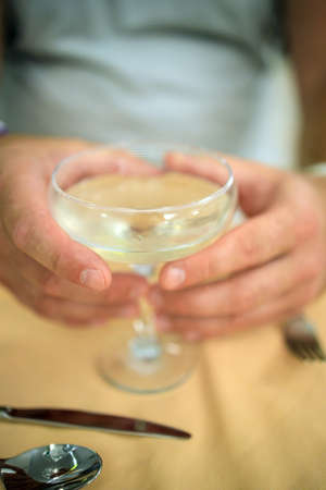 glass with champagne cocktail in male hands, close-up in blurの写真素材