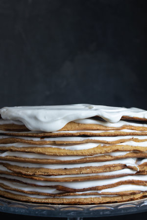 a whole round honey cake on a stand against a dark background.