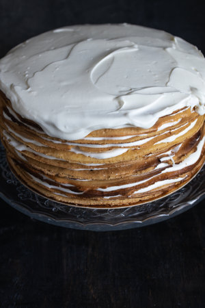 a whole round honey cake on a stand against a dark background.の写真素材