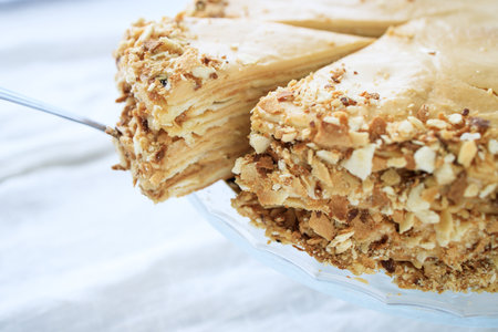 round napoleon cake, with caramel cream and a cut off piece, on a white background. copyspace.の写真素材