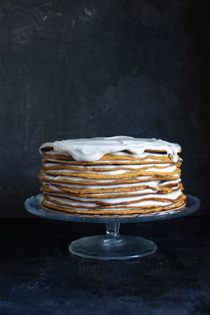 a whole round honey cake on a stand against a dark backgroundの写真素材