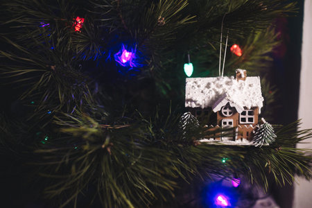 a toy in the form of a cozy house hangs on a Christmas tree