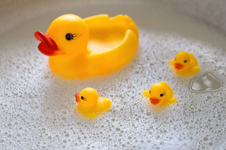 a rubber duck with three ducklings swims in the foam. View from aboveの写真素材