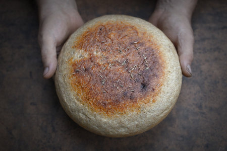 Homemade crusty loave of bread on wooden background. Baker holding fresh bread in the hands. view from above. Dark moodの写真素材