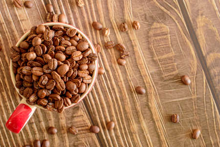 Coffee beans roasted in a cup on a wooden floorの写真素材