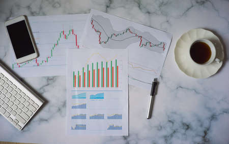 Top view office work desk with financial chart in paper and coffeeFinancial or stock graph chart indicators analysis conceptの写真素材
