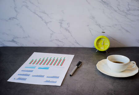 Financial analysis in white paper and clock, coffee cup on working desk, work and relaxing conceptの写真素材