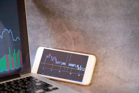 Stock graph analysis in smartphone screen and laptop with copy space at right for textの写真素材