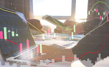 double exposure stock market graph and stock trader are analyzing and trading by laptop and...