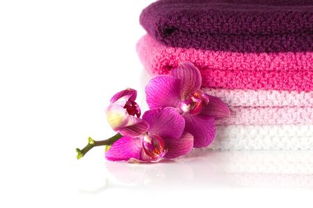 stack of colorful bath towels and purple orchid flowers  isolated on white の写真素材