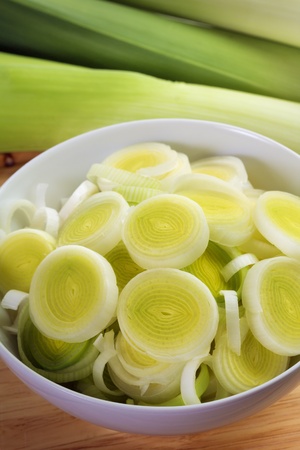 Fresh leeks whole and sliced on a wooden bread boardの写真素材