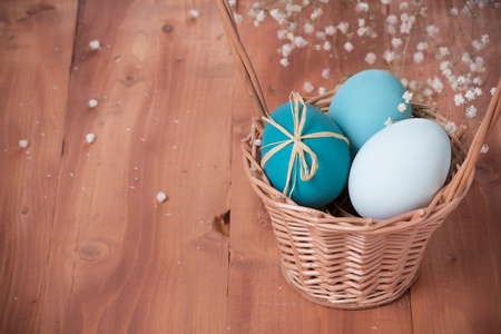 Easter eggs in a basket on wooden backgroundの写真素材