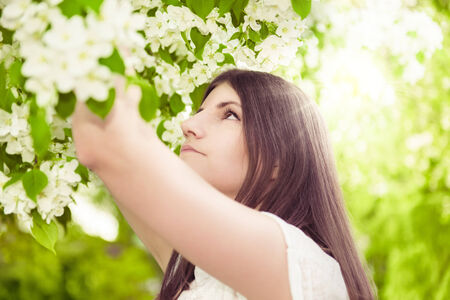 Beautiful spring brunette girl in blooming gardenの写真素材
