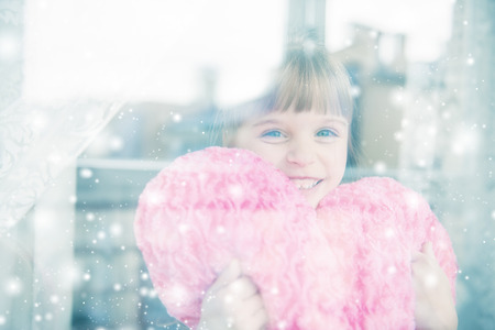 Little girl behind a window. It's snowing outside.