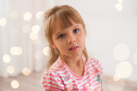 Cute little girl at home. Holiday lights around.の写真素材