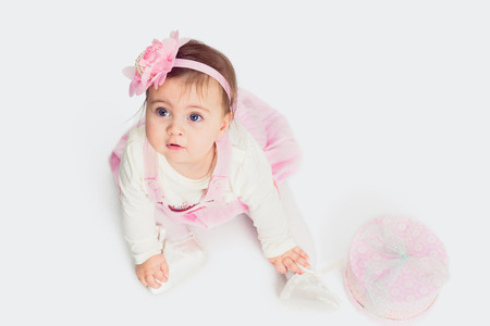 Baby girl sitting on the floor with gift box and looking upの写真素材