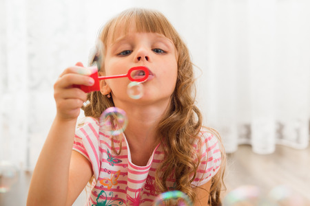 Little girl playing at home with bubble blower.の写真素材